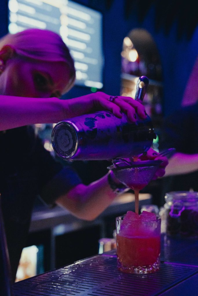 Bilde av en bartender som lager drinker bak baren.