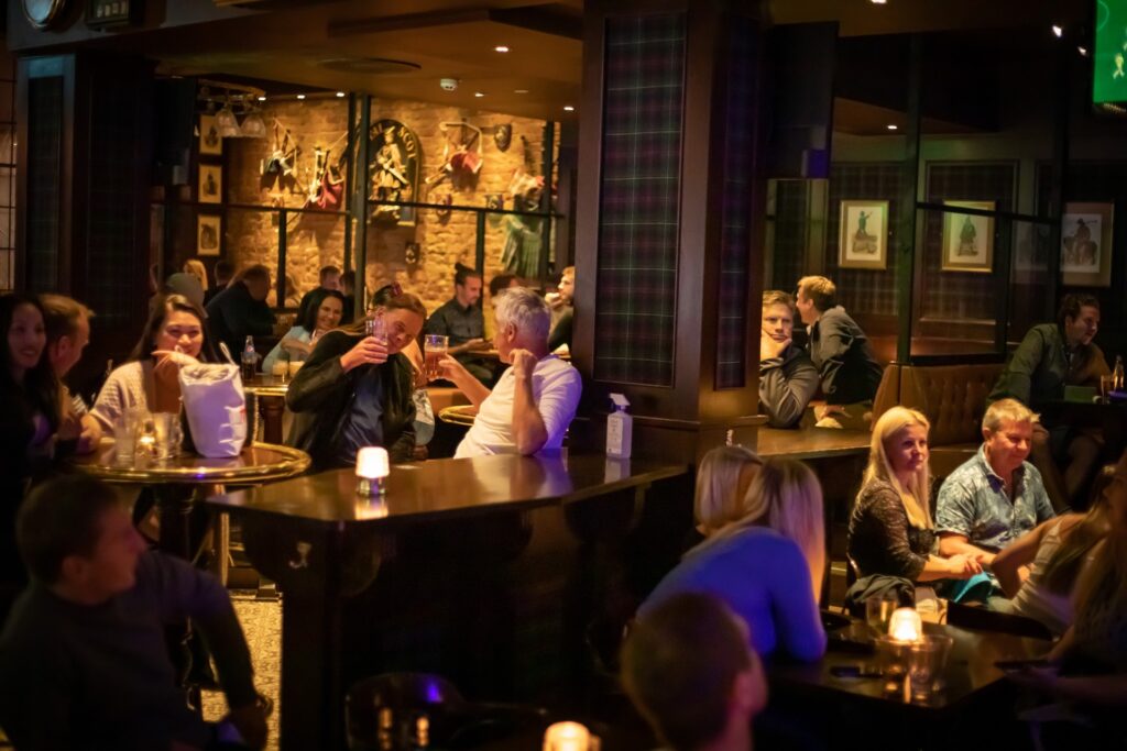The Scotsman pub i 1. etasje, folk smiler og nyter drinker. To karer som skåler i ølglassene
