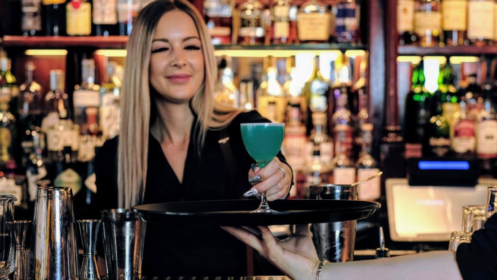 Bartender gir et glass med drikke til en servitør