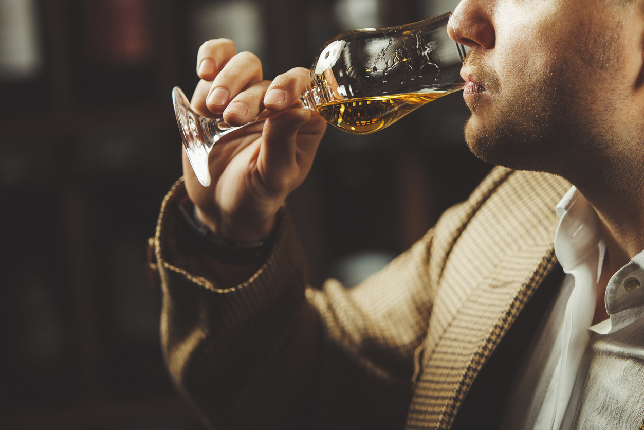 Close-up photo of sommelier tasting whiskey taste on the cellar background.