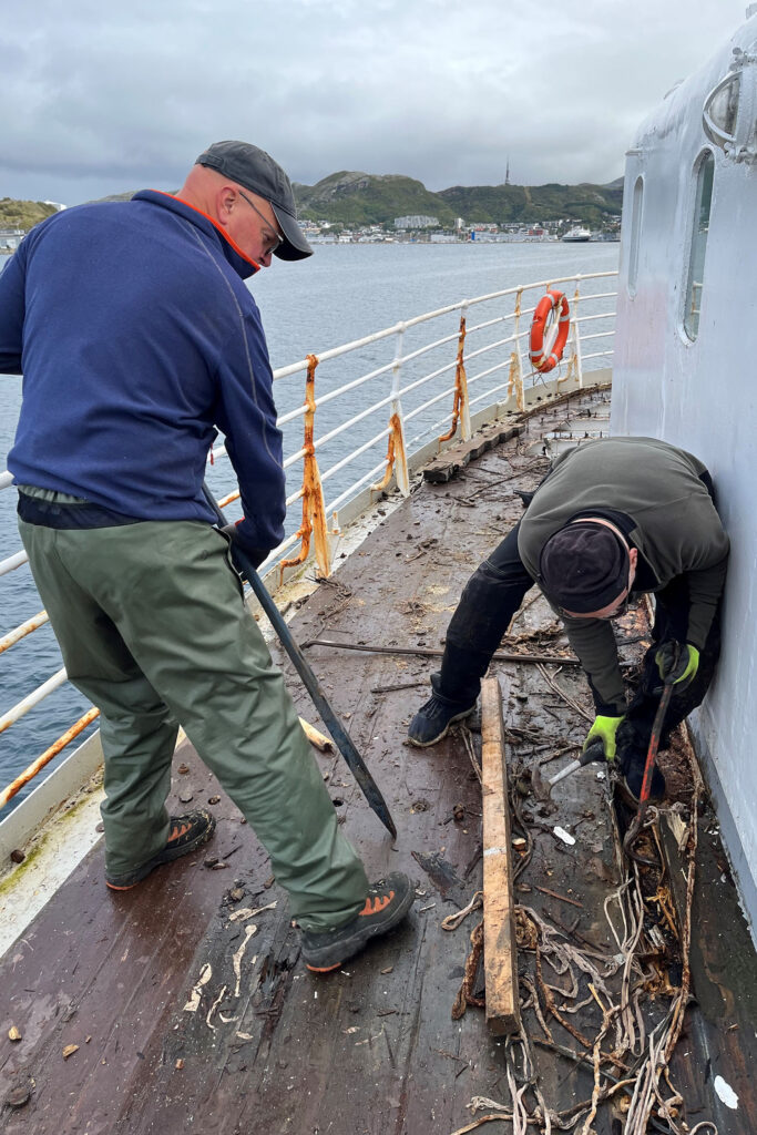 To menn jobber med å rive opp dekket på MS Salten